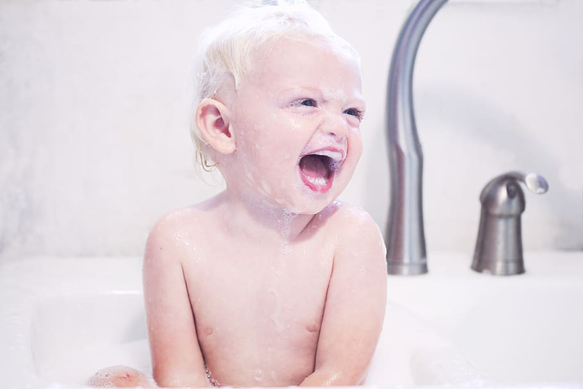bebe riéndose mientras se da un baño