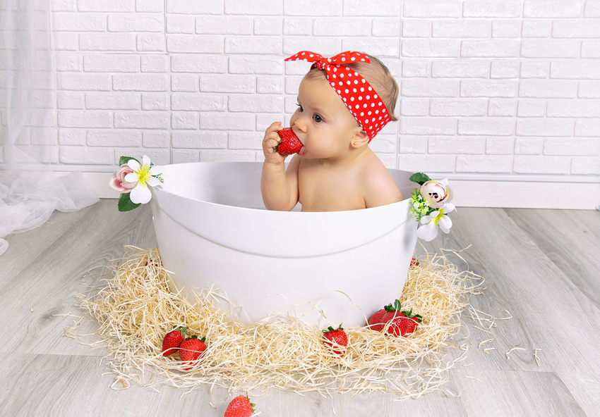 bebé dentro de la bañera comiéndose una fresa